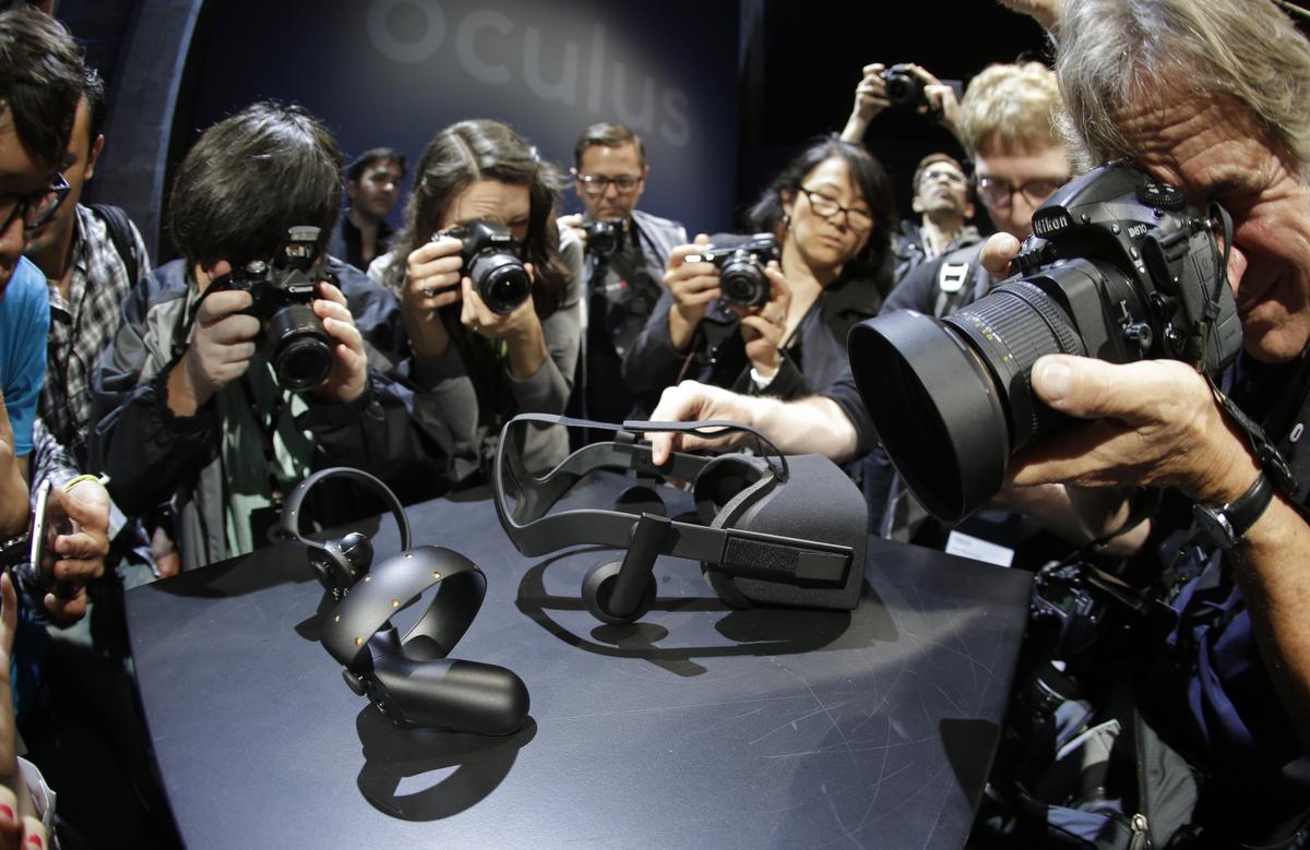 Photographers take pictures of the new Oculus Rift virtual reality headset and touch input device following a news conference Thursday, June 11, 2015, in San Francisco. (AP Photo/Eric Risberg)