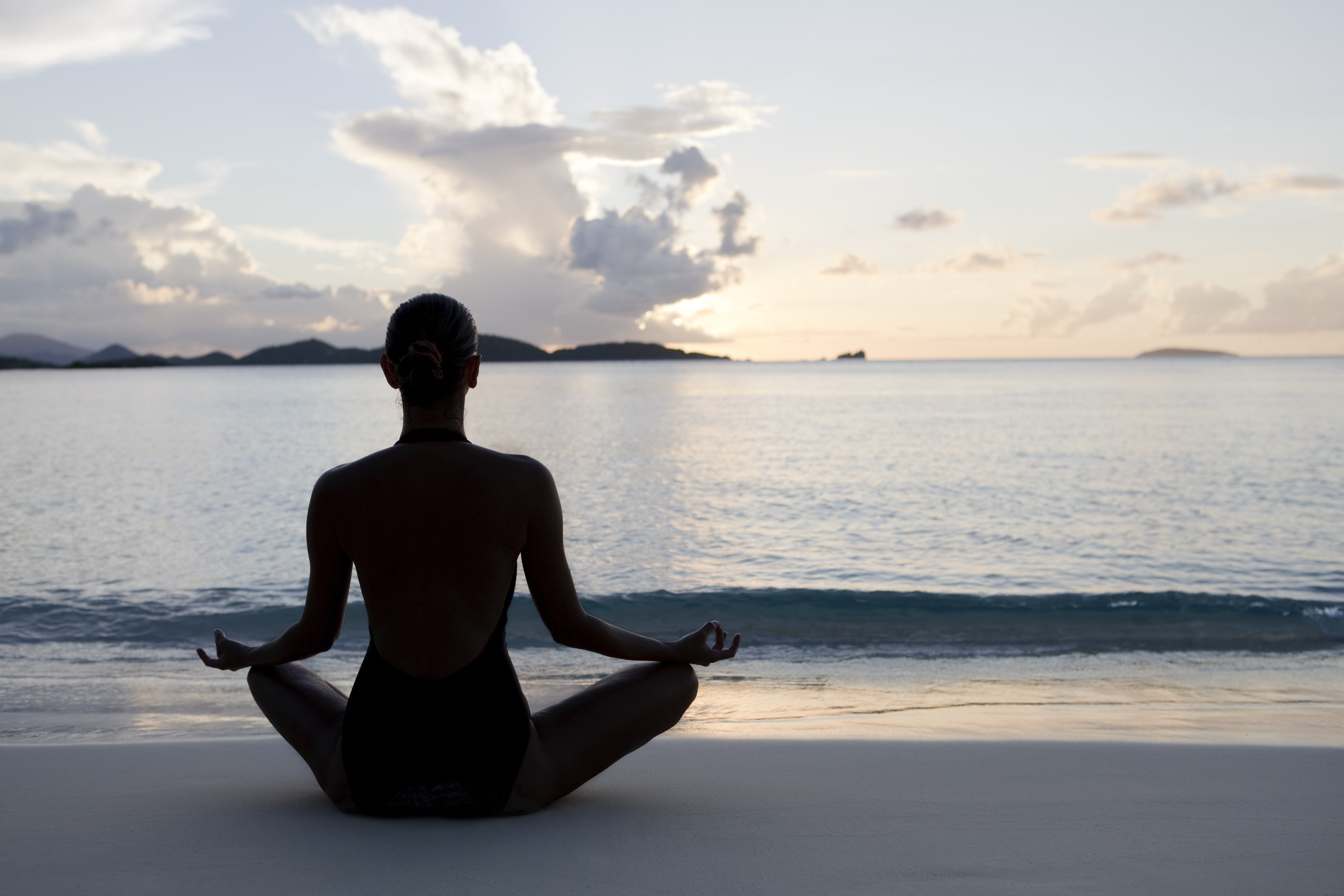 silhouette shot of woman practicing yoga at the Caribbean beach during sunset or sunrise